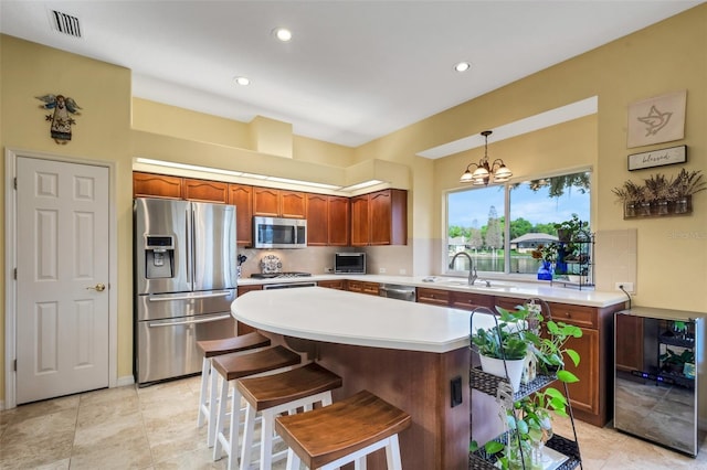 kitchen featuring sink, stainless steel appliances, a notable chandelier, pendant lighting, and a kitchen island