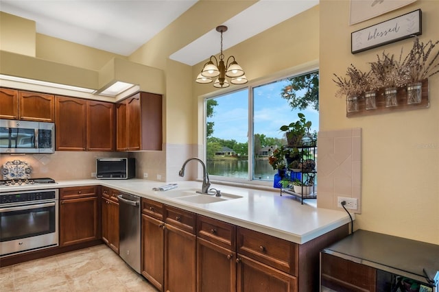 kitchen featuring sink, hanging light fixtures, an inviting chandelier, a water view, and appliances with stainless steel finishes