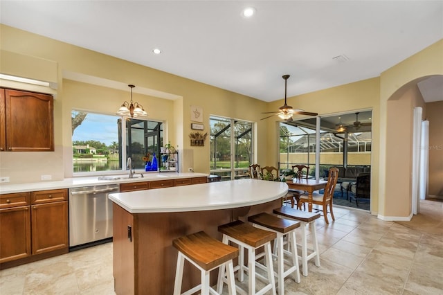 kitchen featuring dishwasher, sink, a kitchen breakfast bar, decorative light fixtures, and a kitchen island