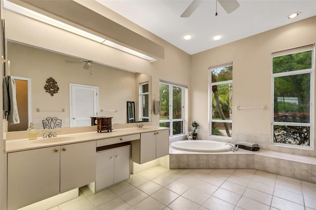 bathroom with tile patterned floors, vanity, ceiling fan, and tiled tub