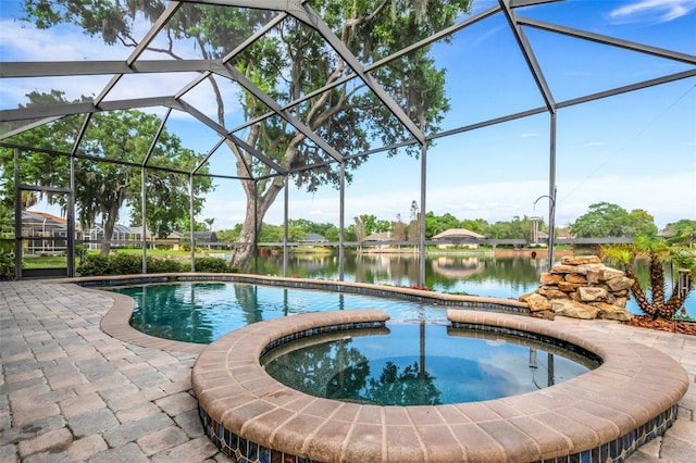 view of swimming pool featuring glass enclosure, a patio area, a water view, and an in ground hot tub