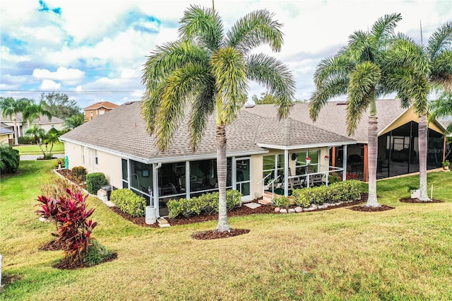 rear view of house featuring a lawn and a sunroom