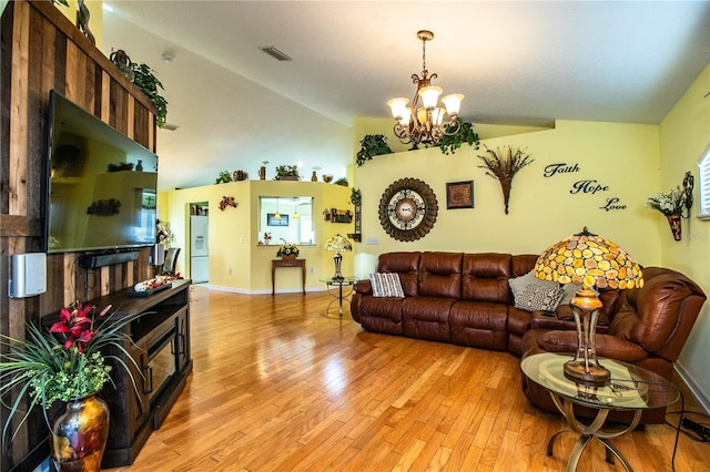 living room featuring a notable chandelier, lofted ceiling, and light wood-type flooring