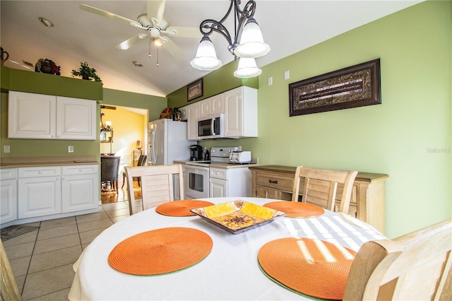 dining space featuring ceiling fan with notable chandelier, lofted ceiling, and light tile patterned floors