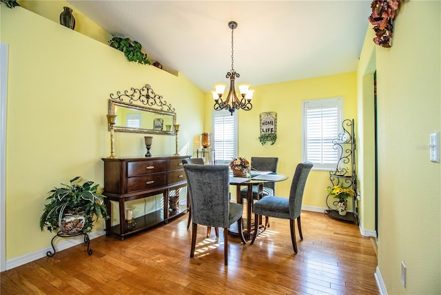 dining area with light hardwood / wood-style floors, lofted ceiling, and an inviting chandelier