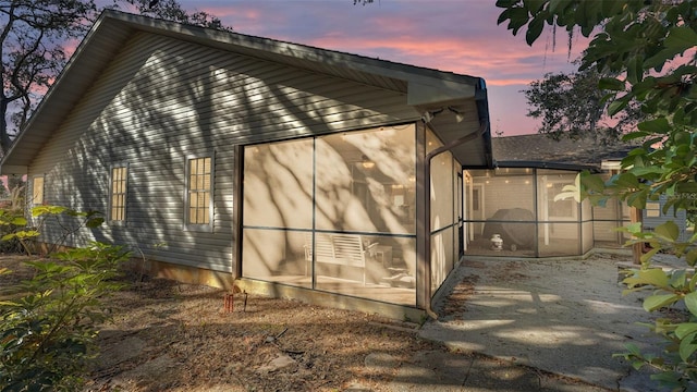 property exterior at dusk featuring a sunroom