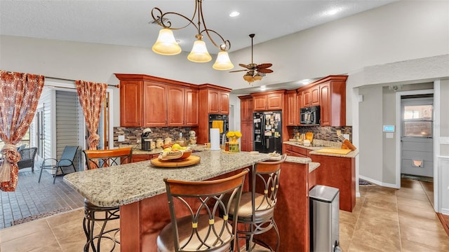 kitchen featuring ceiling fan, decorative light fixtures, decorative backsplash, a kitchen island, and black appliances