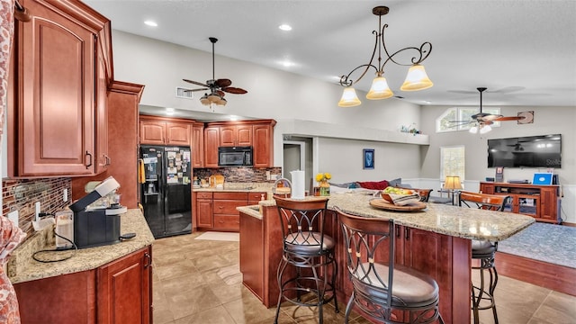 kitchen with light stone countertops, a kitchen breakfast bar, tasteful backsplash, black appliances, and hanging light fixtures