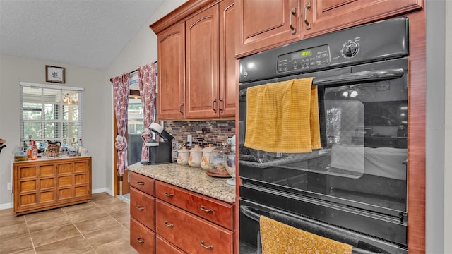 kitchen featuring light stone counters, double oven, lofted ceiling, decorative backsplash, and light tile patterned flooring