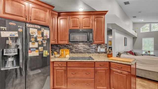 kitchen featuring tasteful backsplash, light stone counters, light tile patterned floors, and black appliances