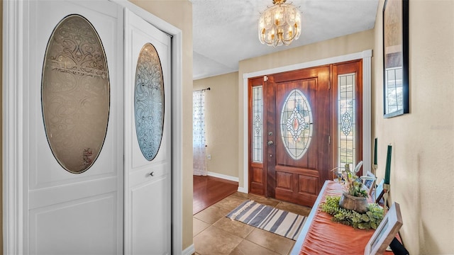 entrance foyer featuring light tile patterned floors, a textured ceiling, and an inviting chandelier