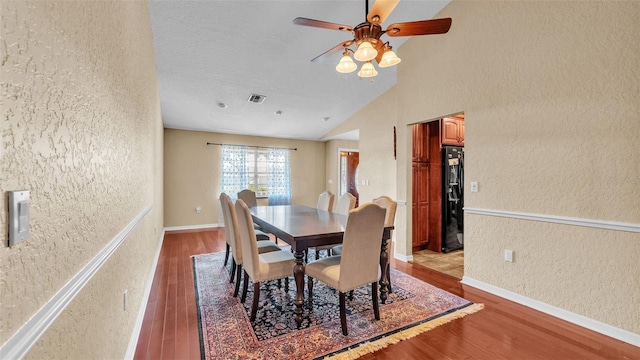 dining space featuring lofted ceiling, ceiling fan, light wood-type flooring, and a textured ceiling