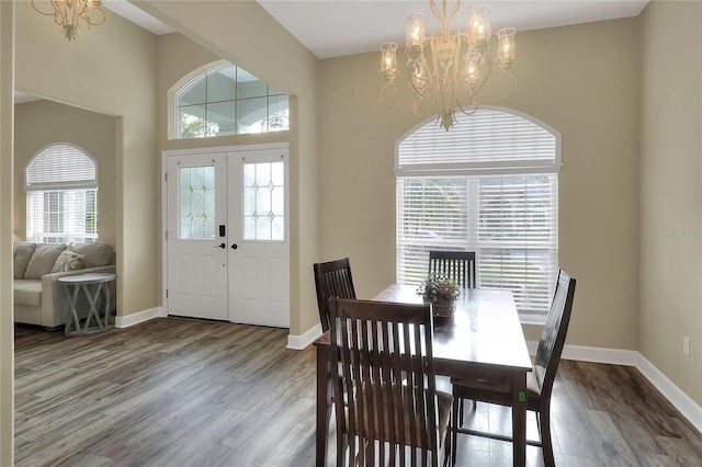 dining space with french doors, wood-type flooring, and a notable chandelier