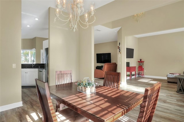 dining area with a notable chandelier, light wood-type flooring, and sink