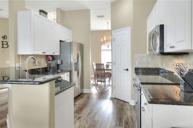 kitchen with white cabinetry, pendant lighting, stainless steel appliances, and an inviting chandelier