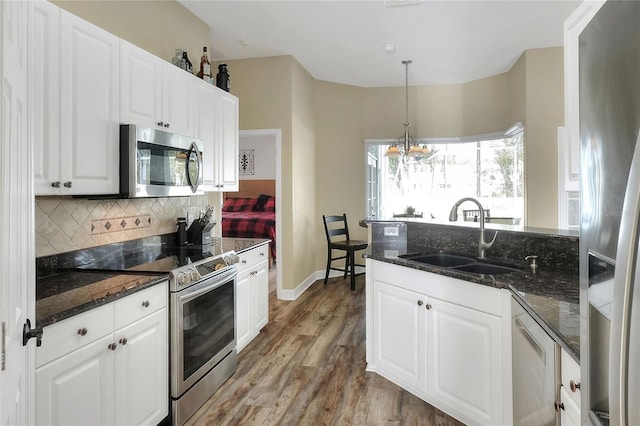 kitchen with pendant lighting, stainless steel appliances, white cabinetry, and sink