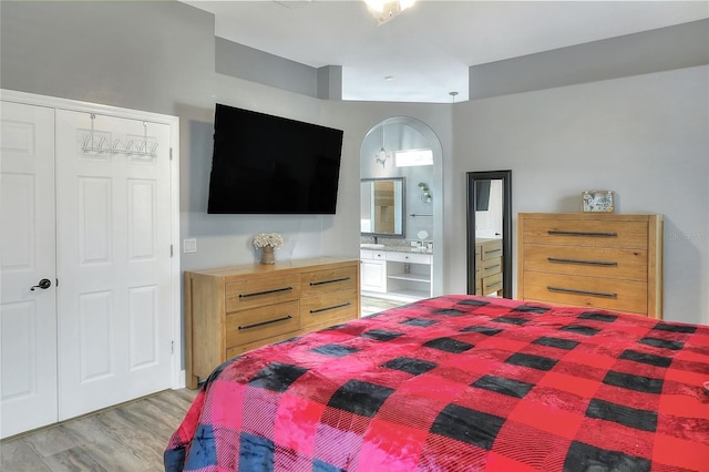 bedroom featuring ensuite bathroom, a closet, and light hardwood / wood-style floors