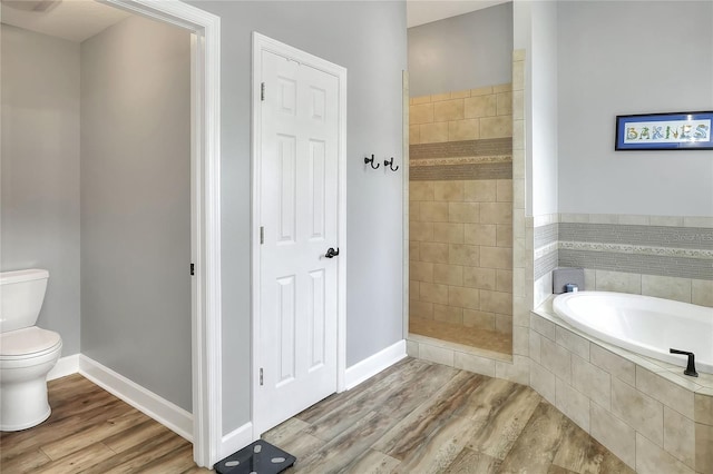 bathroom with hardwood / wood-style floors, toilet, and plus walk in shower