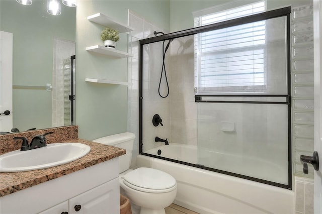 full bathroom featuring vanity, toilet, and bath / shower combo with glass door