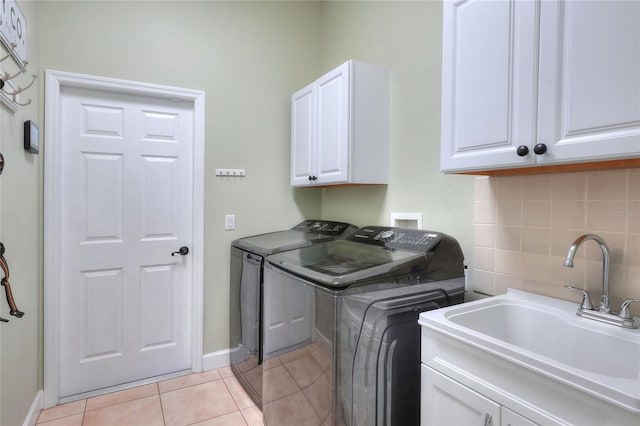 clothes washing area featuring cabinets, light tile patterned floors, sink, and washing machine and clothes dryer