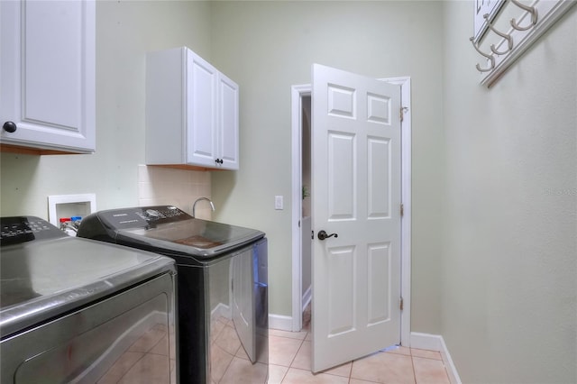 clothes washing area with washer and dryer, light tile patterned floors, and cabinets