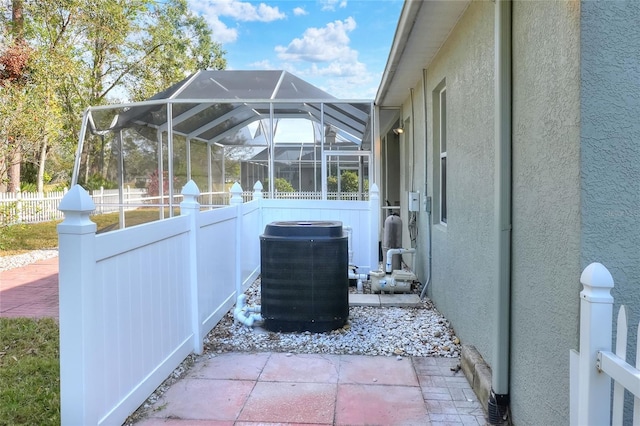 view of patio featuring glass enclosure and central AC