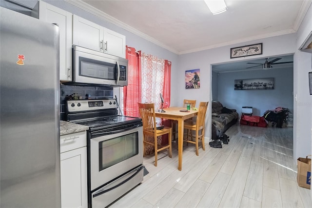 kitchen with white cabinets, crown molding, light hardwood / wood-style flooring, ceiling fan, and appliances with stainless steel finishes