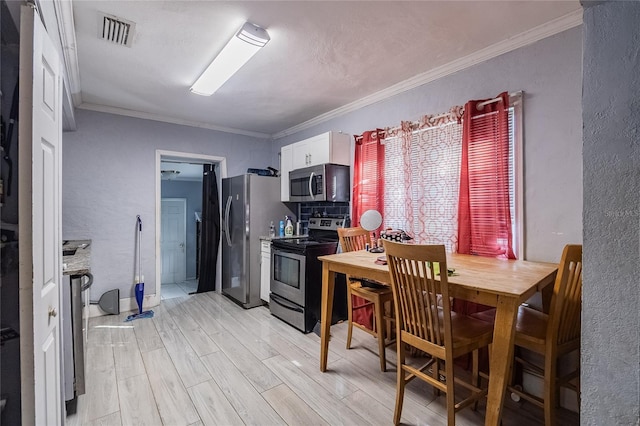 kitchen featuring white cabinets, light wood-type flooring, stainless steel appliances, and ornamental molding