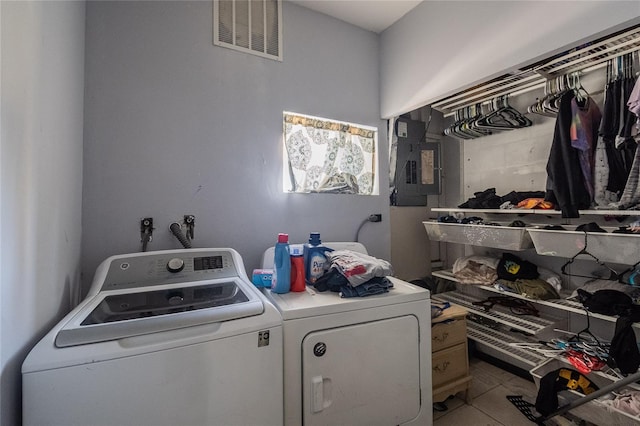 laundry area featuring tile patterned flooring, washing machine and dryer, and electric panel