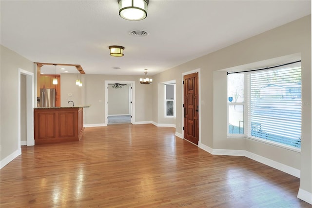 unfurnished living room featuring hardwood / wood-style floors, a notable chandelier, and sink