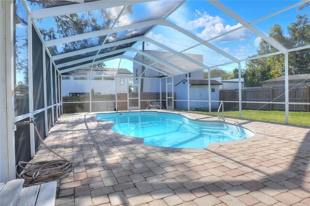 view of pool featuring a lanai, a patio area, a lawn, and a storage unit