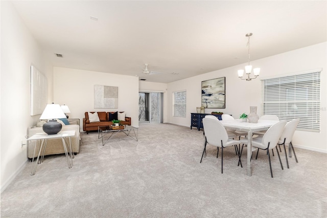 carpeted dining room featuring ceiling fan with notable chandelier