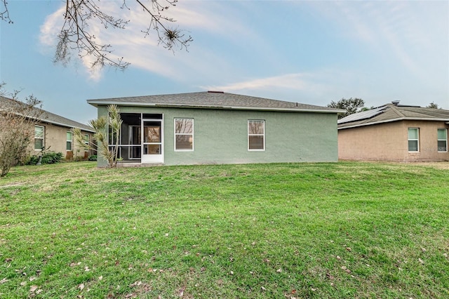 rear view of property featuring a yard and a sunroom