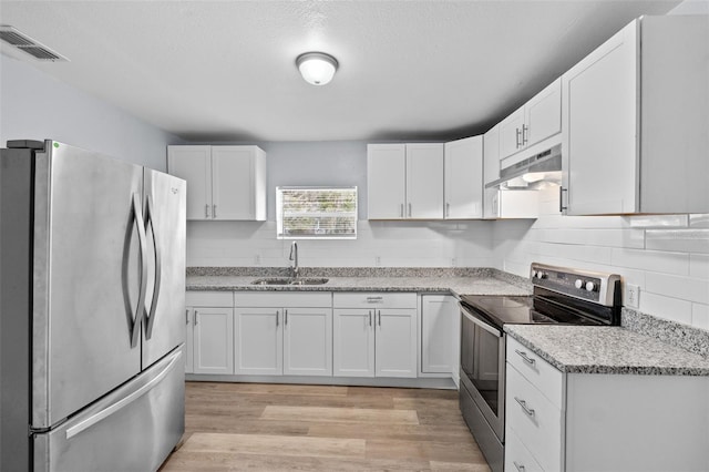 kitchen with white cabinets, stainless steel appliances, light stone counters, and sink