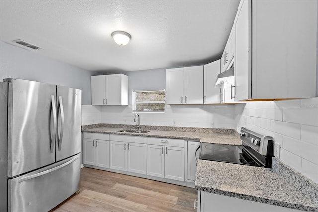 kitchen featuring stove, white cabinetry, stainless steel refrigerator, and sink