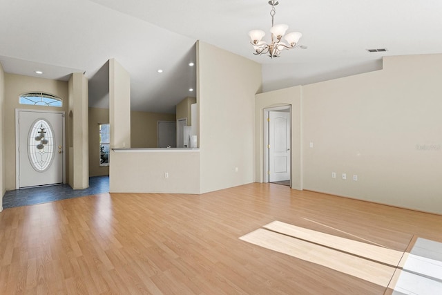 entryway with wood-type flooring, lofted ceiling, and a notable chandelier