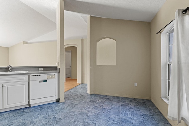 kitchen featuring a textured ceiling, white dishwasher, sink, white cabinets, and lofted ceiling