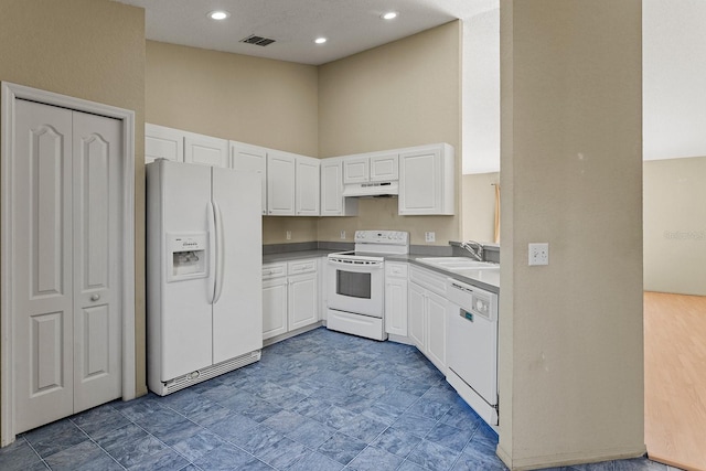 kitchen featuring white cabinets, a towering ceiling, white appliances, and sink