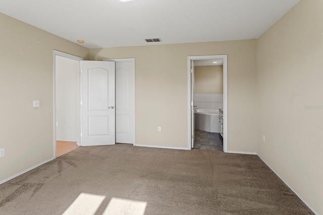 unfurnished bedroom featuring carpet floors, connected bathroom, and a closet