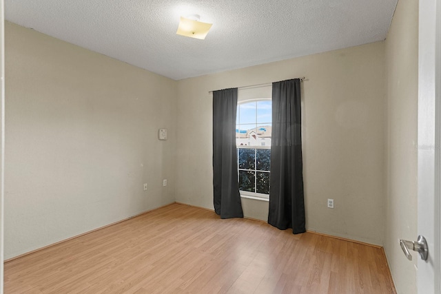 spare room with a textured ceiling and light hardwood / wood-style flooring