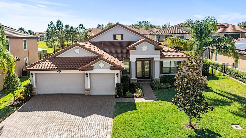 view of front of property with french doors, a garage, and a front lawn