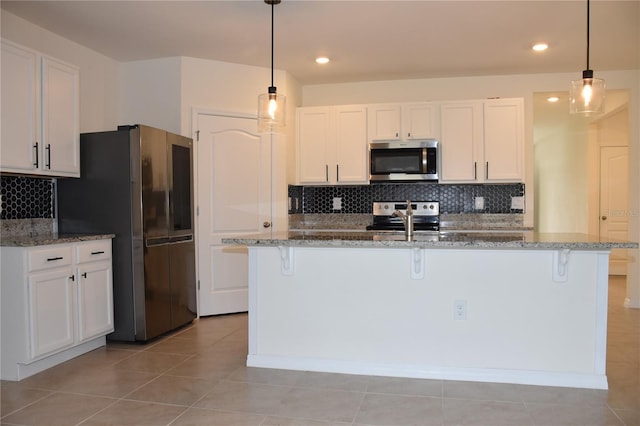 kitchen featuring pendant lighting, stainless steel appliances, white cabinetry, and a kitchen island with sink