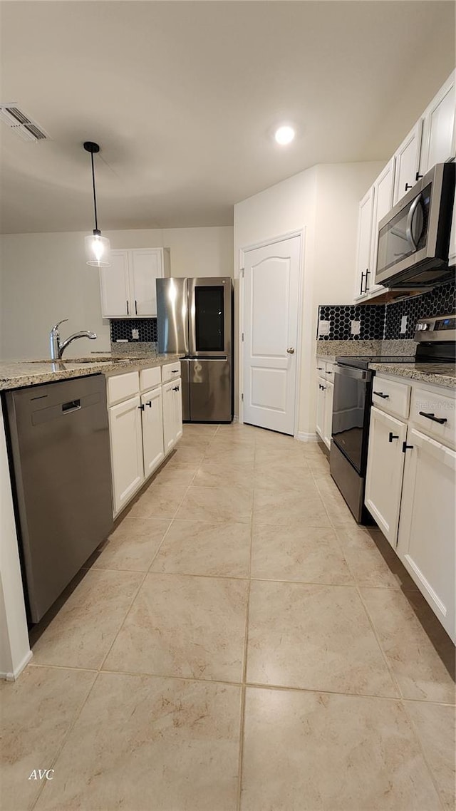 kitchen with appliances with stainless steel finishes, backsplash, light stone counters, white cabinets, and hanging light fixtures