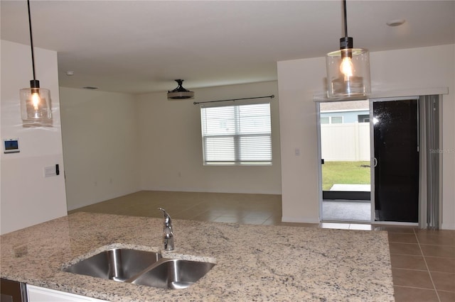 kitchen featuring pendant lighting, tile patterned flooring, light stone counters, and sink