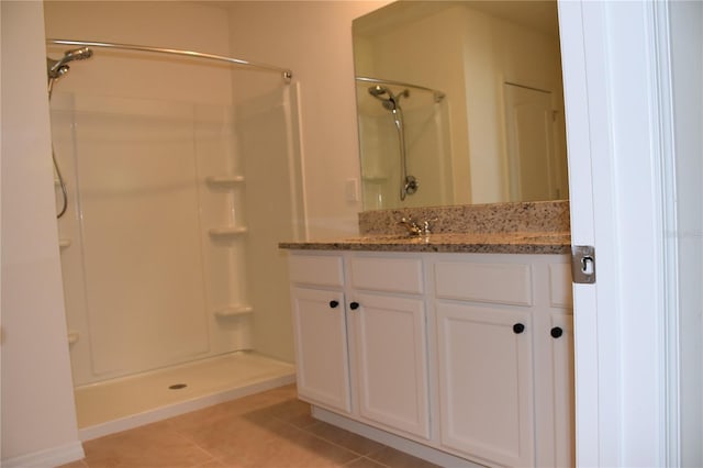 bathroom with tile patterned flooring, vanity, and walk in shower