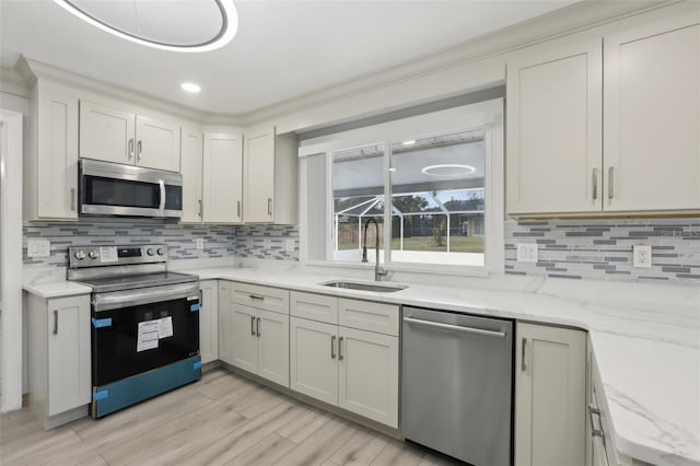 kitchen with light stone countertops, sink, light hardwood / wood-style flooring, decorative backsplash, and appliances with stainless steel finishes