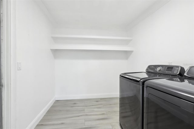 washroom with light wood-type flooring, washing machine and dryer, and ornamental molding