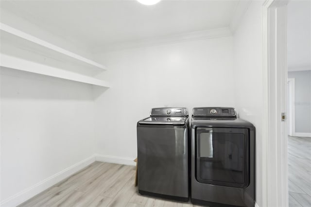 laundry area with washer and clothes dryer, light hardwood / wood-style floors, and ornamental molding