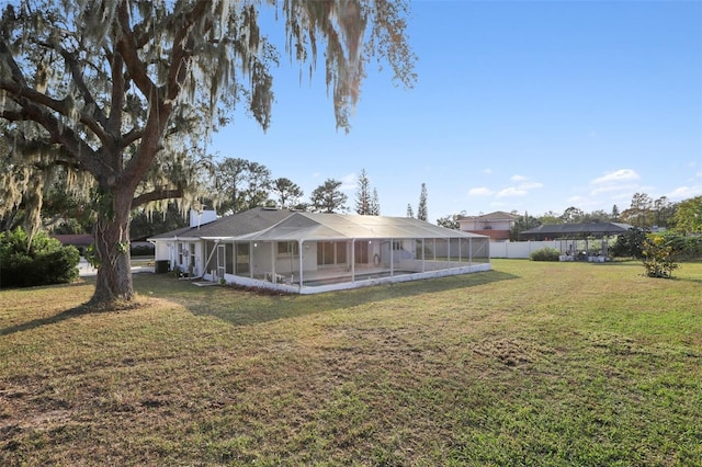 rear view of property featuring a lanai and a lawn