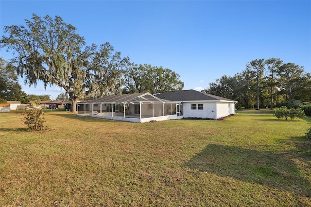 rear view of property with glass enclosure and a yard